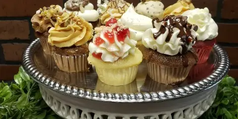 An assortment of decorated cupcakes with various frostings and toppings arranged on a silver cake stand.