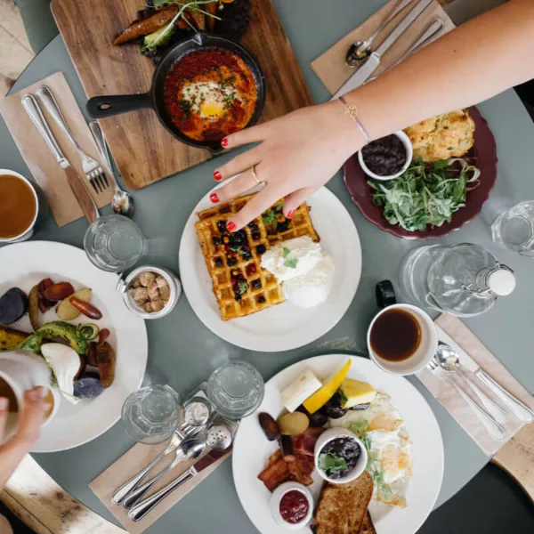 Overhead view of a table set with various catering dishes including waffles, shakshuka, and a breakfast platter.