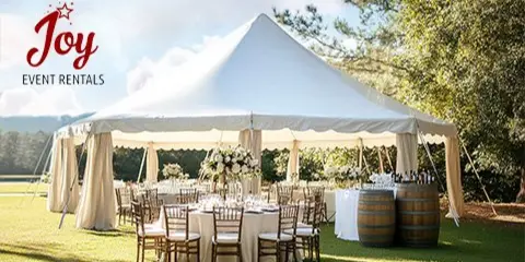 A white event tent set up on a lawn with tables, chairs, and floral centerpieces.