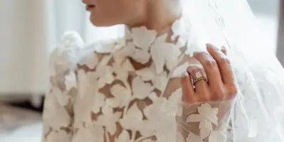 Bride in profile wearing a lace wedding dress and veil with styled hair and makeup