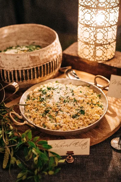 A close-up of a catering dish labeled 'Chopped Clafoutis' served in a metal pan with a decorative lantern and greenery in the background.