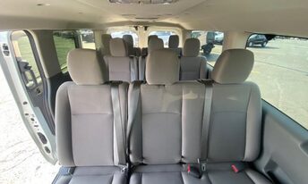 Interior view of a passenger van showing rows of bench seating and headrests.