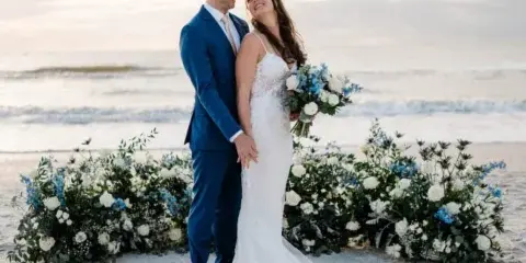 A bride and groom standing on a beach during a wedding ceremony.
