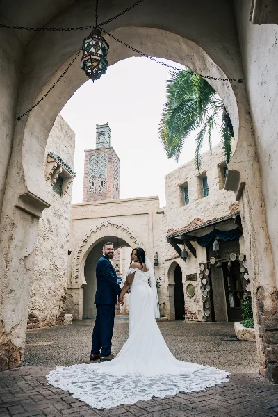 A bride and groom standing together in a courtyard with Moroccan-style architecture.