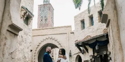 A bride and groom standing together in a courtyard with Moroccan-style architecture.