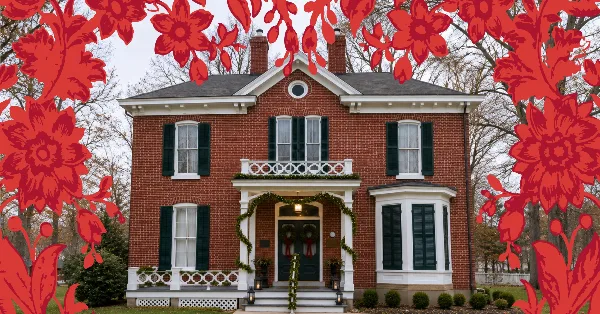 Exterior view of a two-story red brick historic house with white trim and green shutters, decorated with holiday garlands.