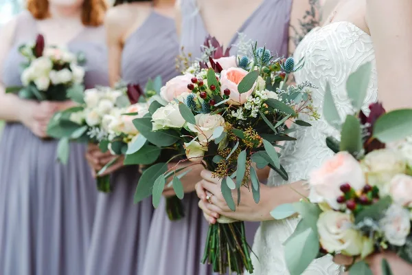 Bride and bridesmaids holding custom wedding bouquets with roses, eucalyptus, and greenery.