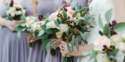 Bride and bridesmaids holding custom wedding bouquets with roses, eucalyptus, and greenery.