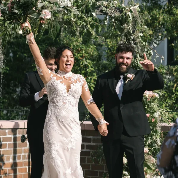 A bride and groom celebrating at a wedding reception with floral decorations in the background.