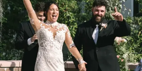 A bride and groom celebrating at a wedding reception with floral decorations in the background.