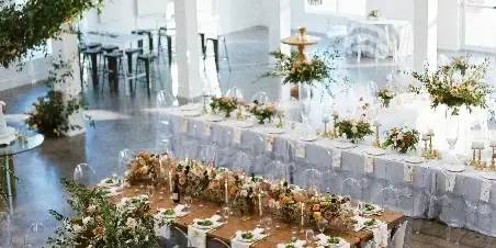 Wedding reception hall with long tables, floral arrangements, and a large crystal chandelier.