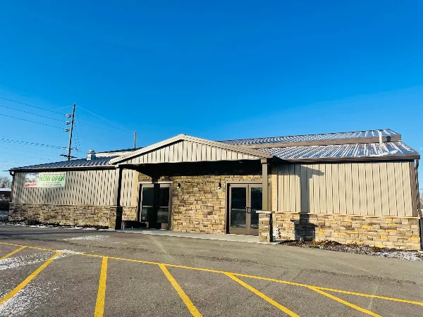 Exterior view of a modern event venue building with stone and metal siding under a clear blue sky.