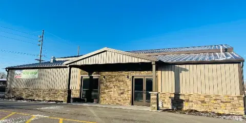 Exterior view of a modern event venue building with stone and metal siding under a clear blue sky.