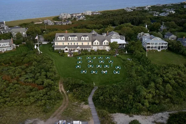 Aerial view of The Wauwinet resort building situated on a large green lawn adjacent to the ocean and coastal dunes.