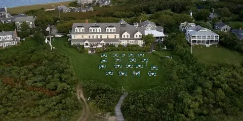 Aerial view of The Wauwinet resort building situated on a large green lawn adjacent to the ocean and coastal dunes.