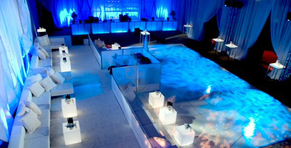 A wedding event venue featuring a large, illuminated LED dance floor and blue ambient lighting.