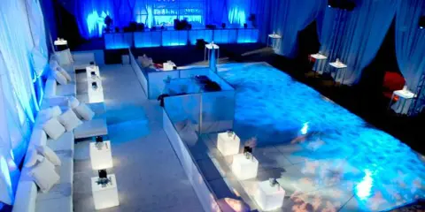 A wedding event venue featuring a large, illuminated LED dance floor and blue ambient lighting.