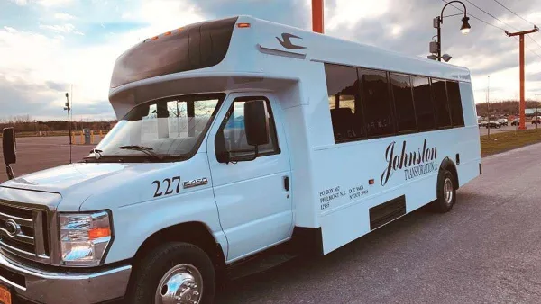 A white shuttle bus with Johnston Transportation branding parked in a lot.