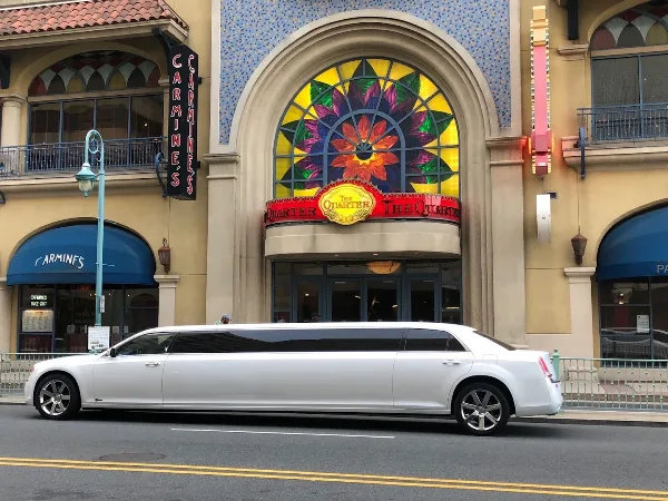 A white stretch limousine parked on a street in front of a building with a stained-glass window.