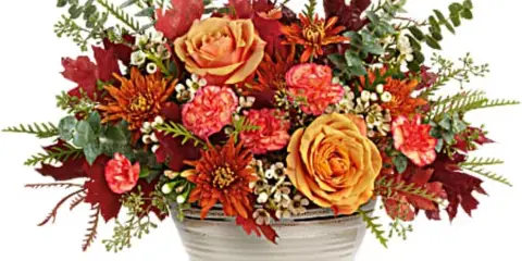 Autumn floral arrangement in a white ceramic bowl with orange and pink blooms