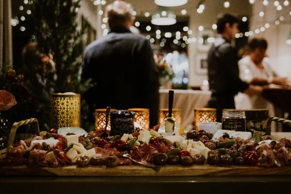 A large, artfully arranged charcuterie board with meats, cheeses, and olives at a catered event.