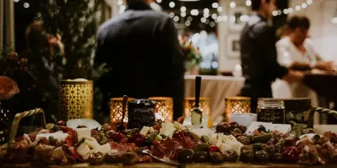 A large, artfully arranged charcuterie board with meats, cheeses, and olives at a catered event.