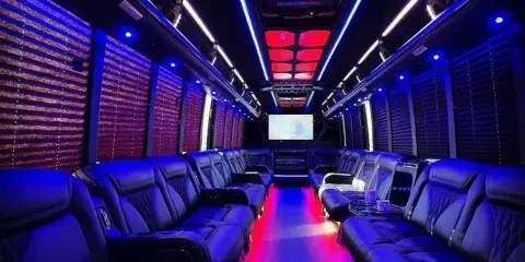 Interior of a luxury limousine with black leather seats and blue and red LED lighting.