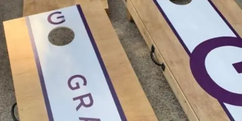 Custom wooden cornhole boards with purple and white branding