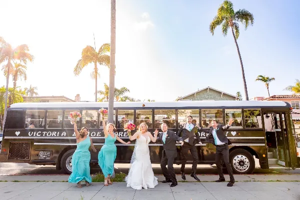 A wedding party posing with a black school bus
