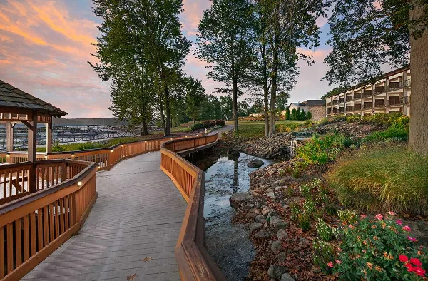 Exterior view of the Fourwinds Lakeside Inn & Marina showing the hotel building, wooden walkway, and Lake Monroe at sunset.