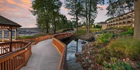 Exterior view of the Fourwinds Lakeside Inn & Marina showing the hotel building, wooden walkway, and Lake Monroe at sunset.