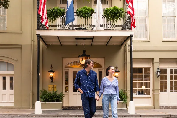 Exterior view of the Bienville House Hotel entrance in the French Quarter with a couple walking in front.