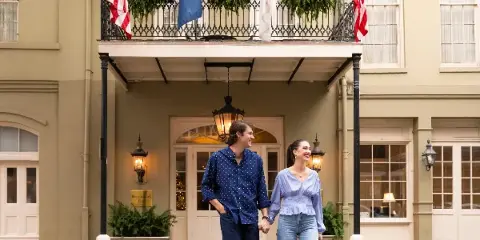Exterior view of the Bienville House Hotel entrance in the French Quarter with a couple walking in front.