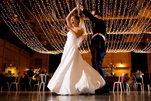 Bride and groom dancing at a wedding reception under hanging string lights