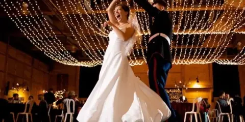 Bride and groom dancing at a wedding reception under hanging string lights