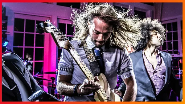A live band member playing an electric guitar on stage during a performance.
