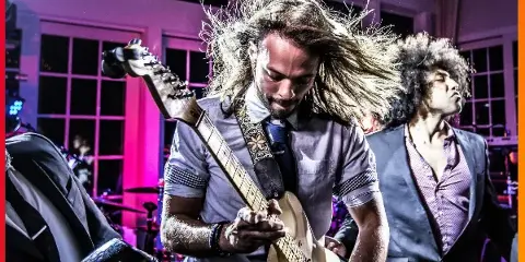 A live band member playing an electric guitar on stage during a performance.