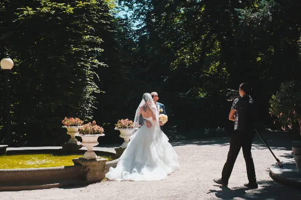 A videographer filming a bride and groom in a garden setting