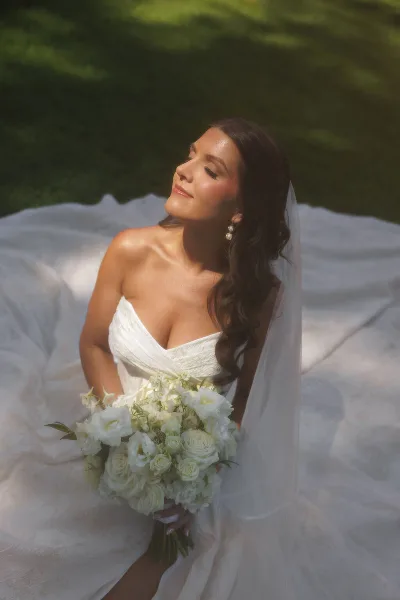 Bride with romantic wavy hair and natural soft glam makeup holding a white bouquet