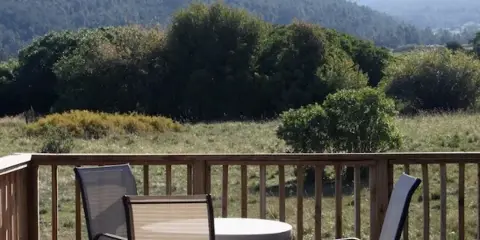 A wooden deck with a table and chairs overlooking a scenic mountain landscape.