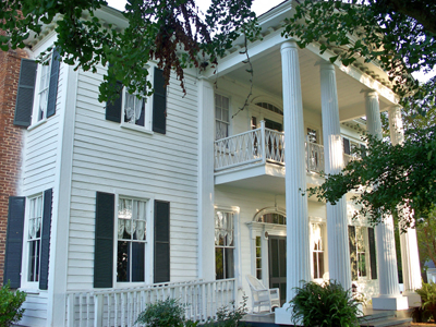 Exterior view of a historic white two-story home with a large porch and columns.