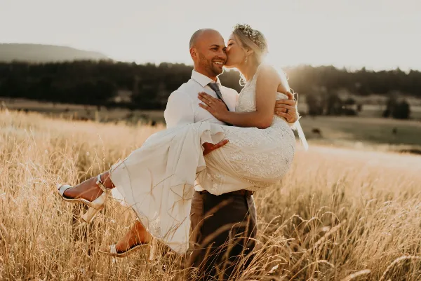 A bride and groom embracing in a golden field during a wedding.