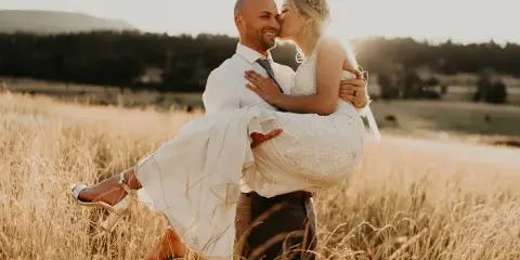 A bride and groom embracing in a golden field during a wedding.