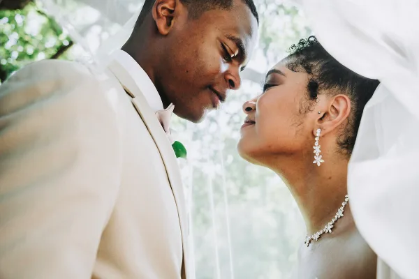A close-up, candid photograph of a groom and bride looking at each other affectionately during their wedding.