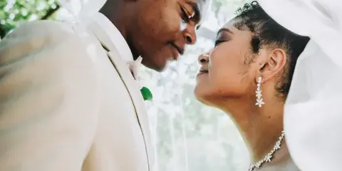 A close-up, candid photograph of a groom and bride looking at each other affectionately during their wedding.