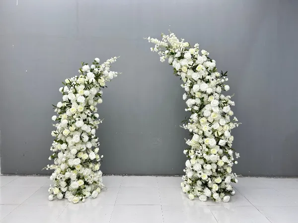 A white floral arch standing against a gray wall.
