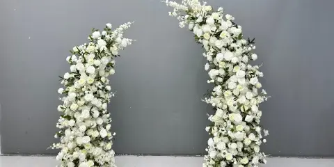 A white floral arch standing against a gray wall.