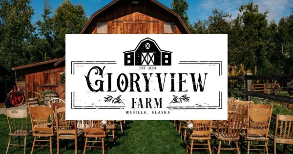 Exterior view of the Gloryview Farm rustic barn wedding venue with outdoor seating and signage.