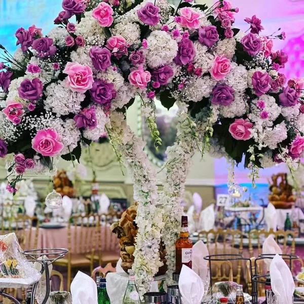 A decorated wedding venue featuring a large floral arch and set banquet tables.