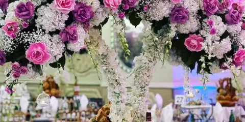 A decorated wedding venue featuring a large floral arch and set banquet tables.